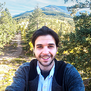 Rick Hill visiting the Rocky Mountains on a beautiful sunny day with a scenic view of the mountains in the background.